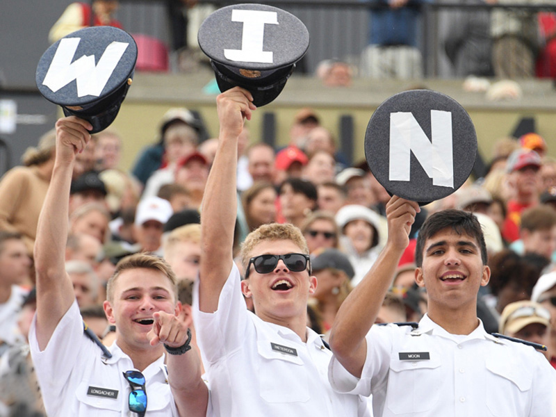 小黄鸭视频 cadets in stands cheer a sports team and hold up hats that spell out W I N