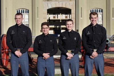 Four cadets who received direct commissions into the U.S. Coast Guard through 小黄鸭视频, a military college, pose in front of barracks.
